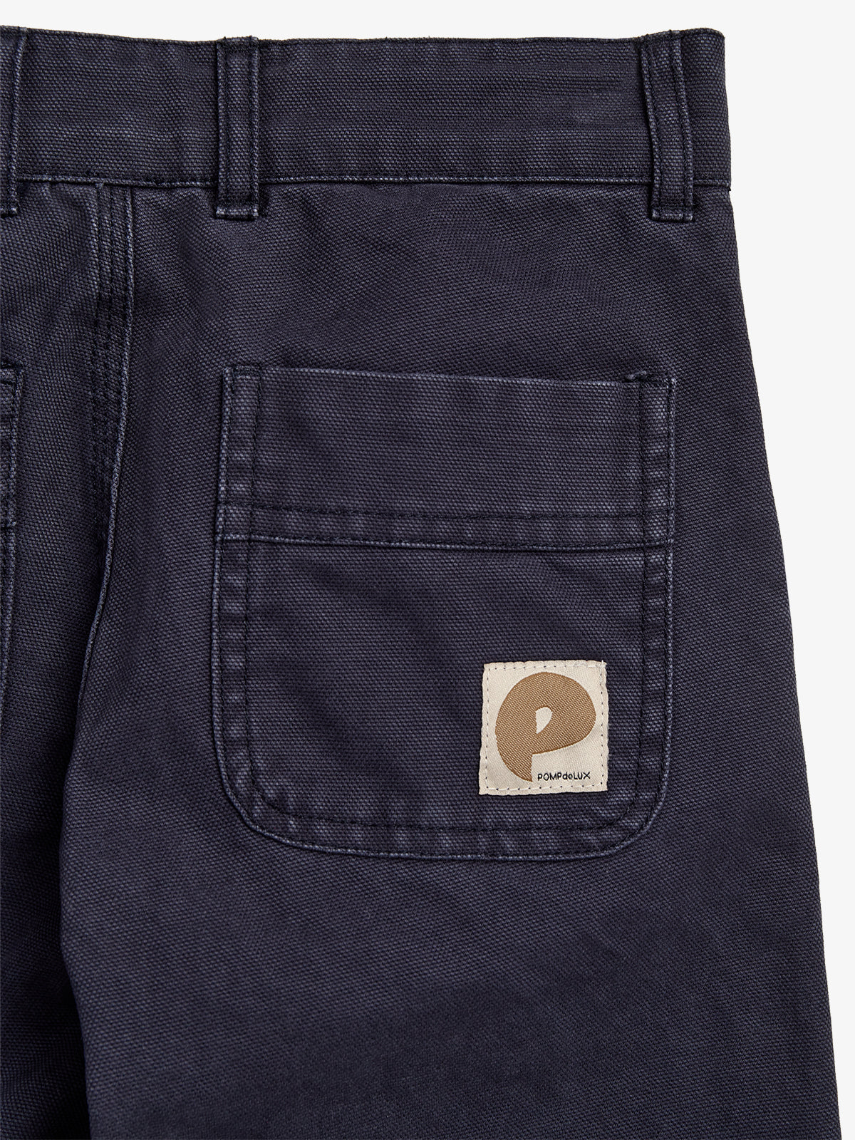 Dark navy fabric with a stitched rectangular back pocket and belt loops; a beige patch shows a stylized letter "P" and the text "POMPéLUX" in the bottom right corner.