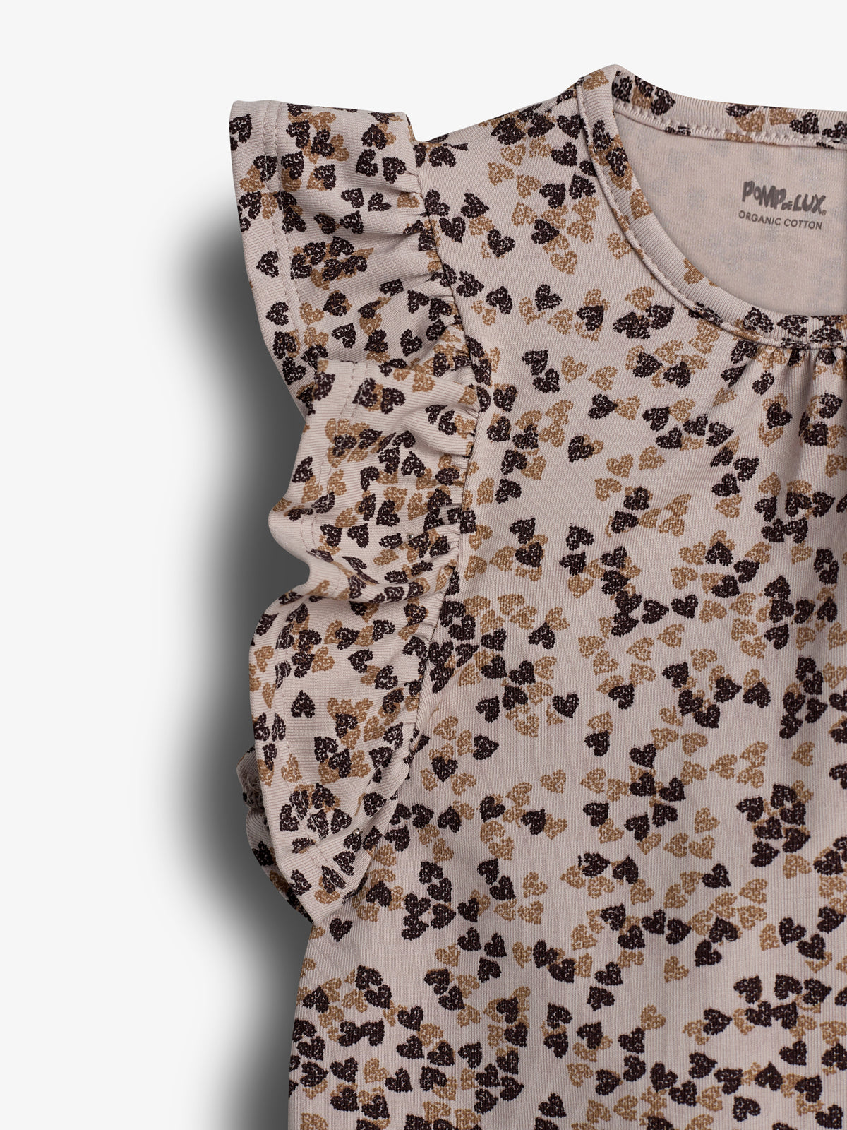 A sleeveless blouse features a ruffled shoulder detail with a pattern of black and brown floral designs on a beige background. Text reads: "POMPdeLUX ORGANIC COTTON."