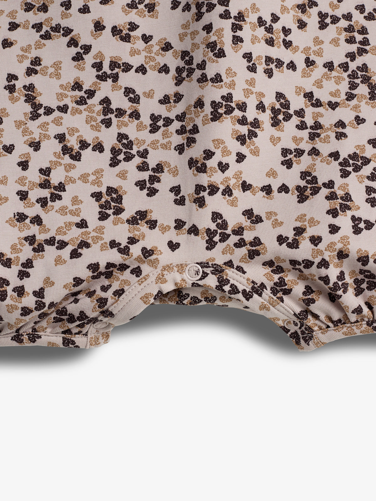 A fabric with a pattern of scattered small brown and gold leaf-like prints on a light background. The fabric has a button closure at the bottom edge.
