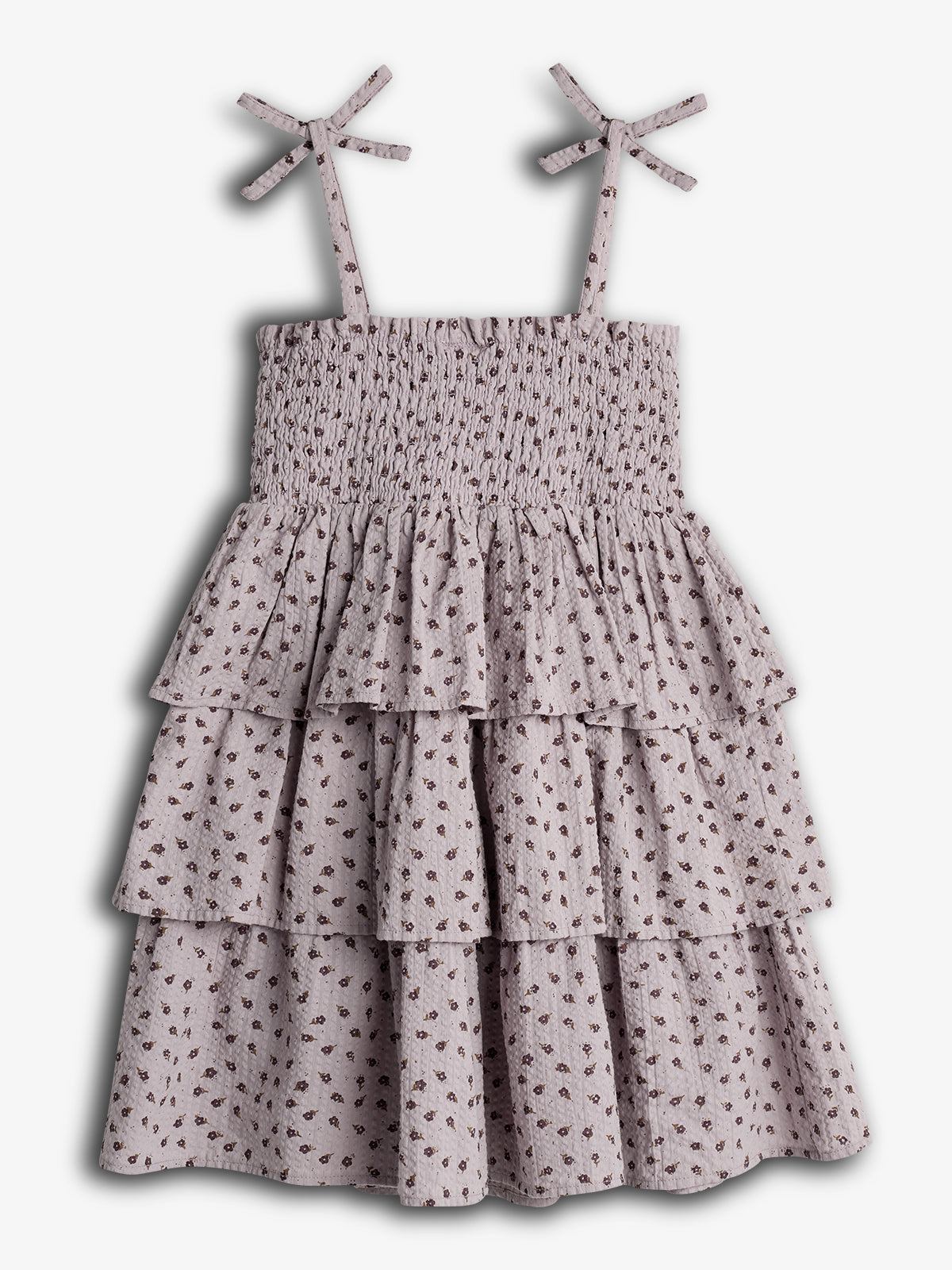 A sleeveless, tiered ruffle dress with floral patterns and smocked bodice, featuring bow-tied shoulder straps. Displayed against a plain white background.
