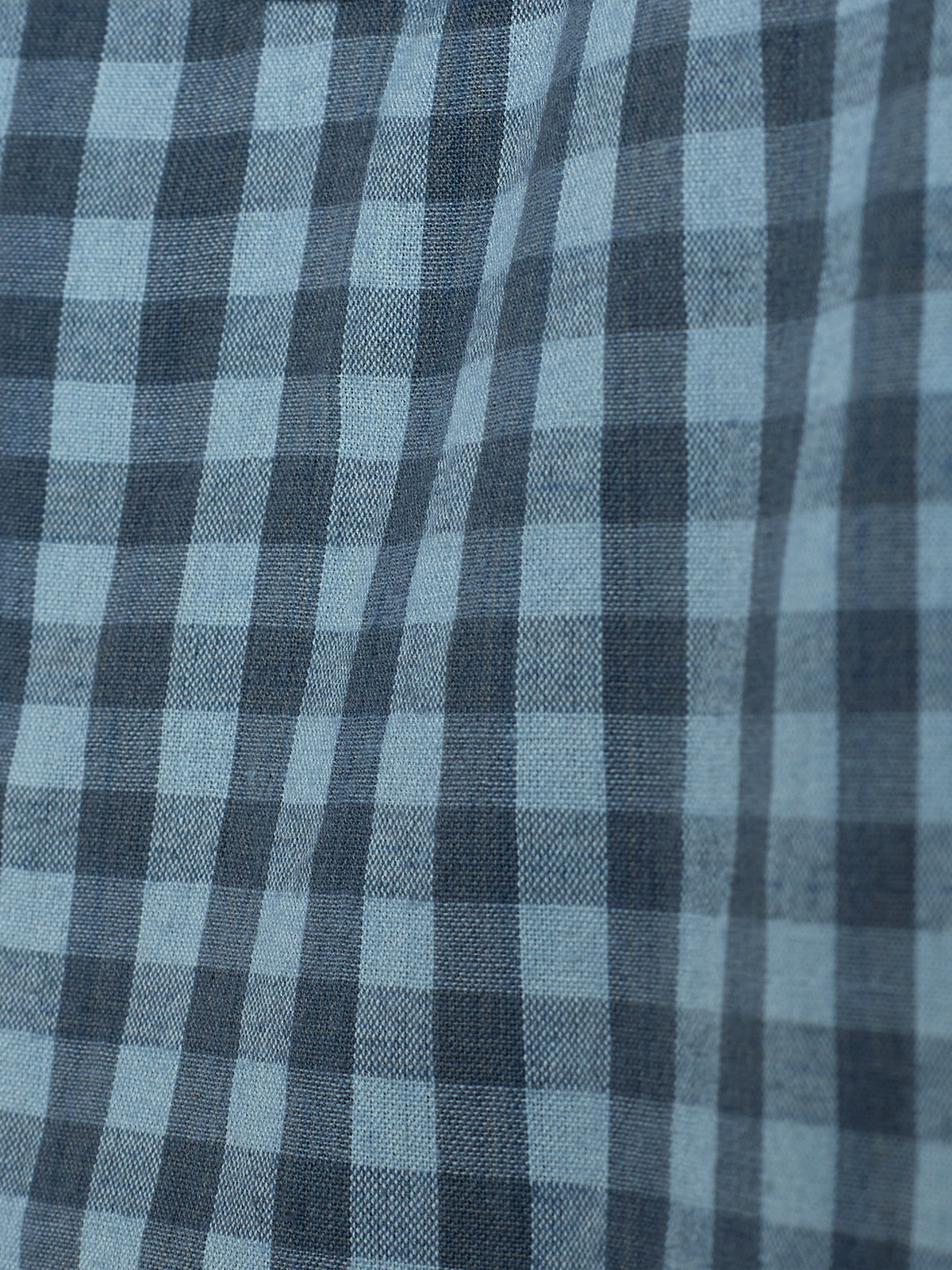 A fabric displays a blue and gray checkered pattern with alternating light and dark squares, creating a textured and slightly wavy surface.