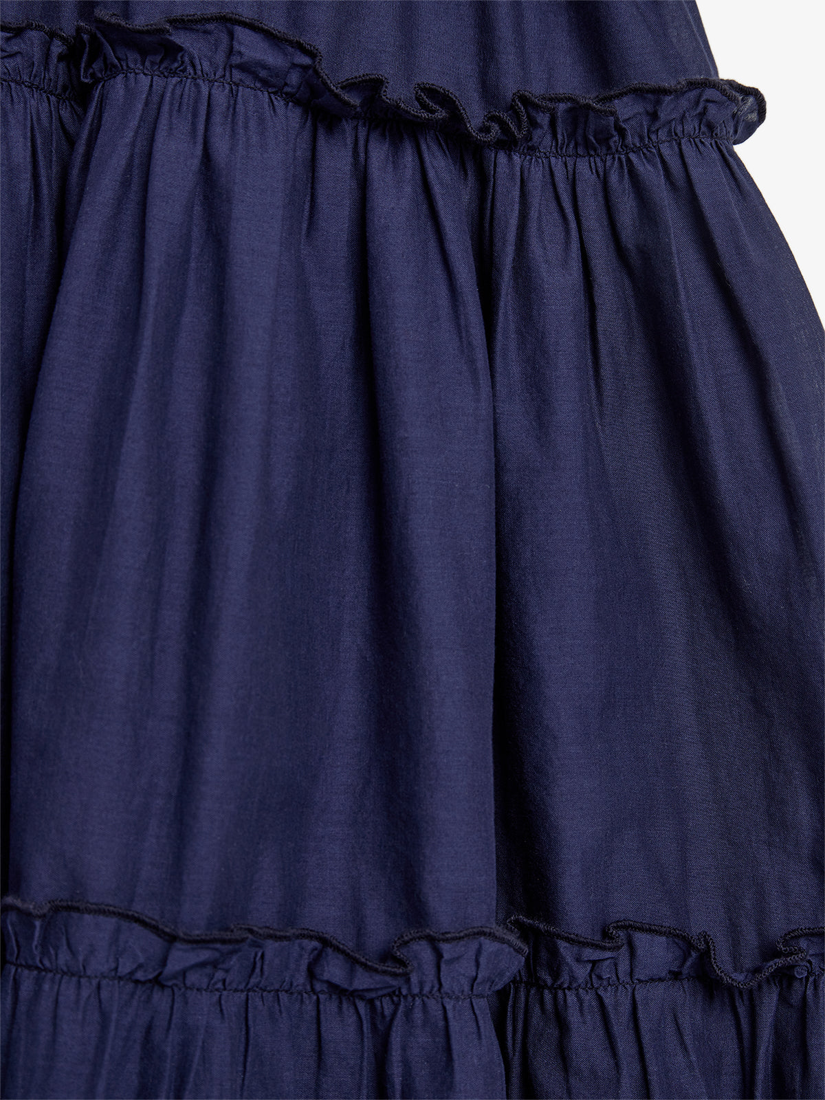 A navy blue fabric with gathered ruffles creates a layered texture, displayed against a plain background.