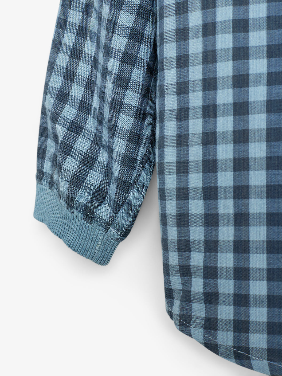 A section of a blue and black checkered fabric shirt with long sleeves, shown with a cuffed end, set against a plain white background.